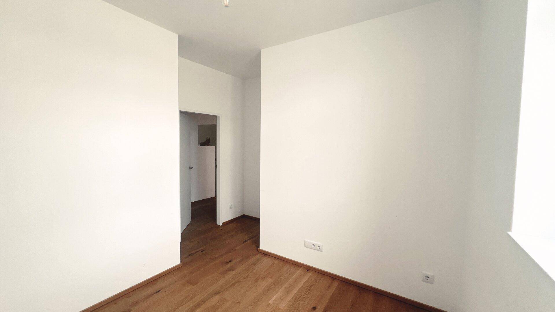 Unmöbliertes Zimmer mit Holzboden und weiß gestrichenen Wänden, ideal für individuelle Gestaltung.