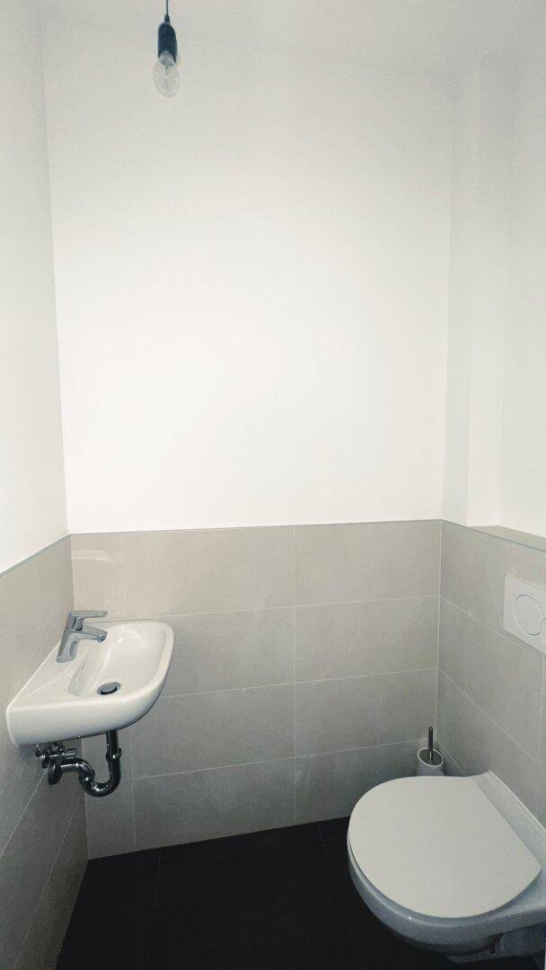 Kleines Gäste-WC mit wandhängender Toilette und Handwaschbecken, in schlichtem Design.
