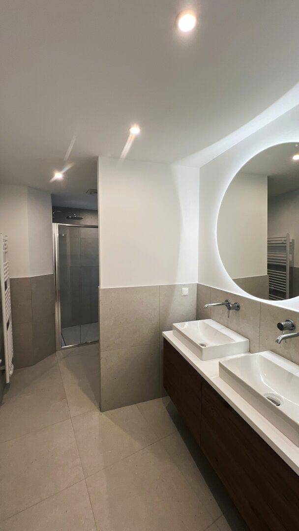 Modernes Badezimmer mit Doppelwaschbecken, Dusche und beheiztem Handtuchhalter.