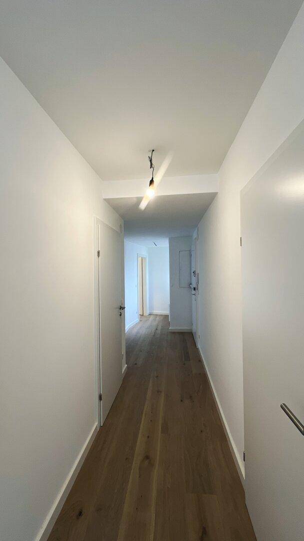 Langer, heller Flur mit Holzboden und Türen zu verschiedenen Räumen.