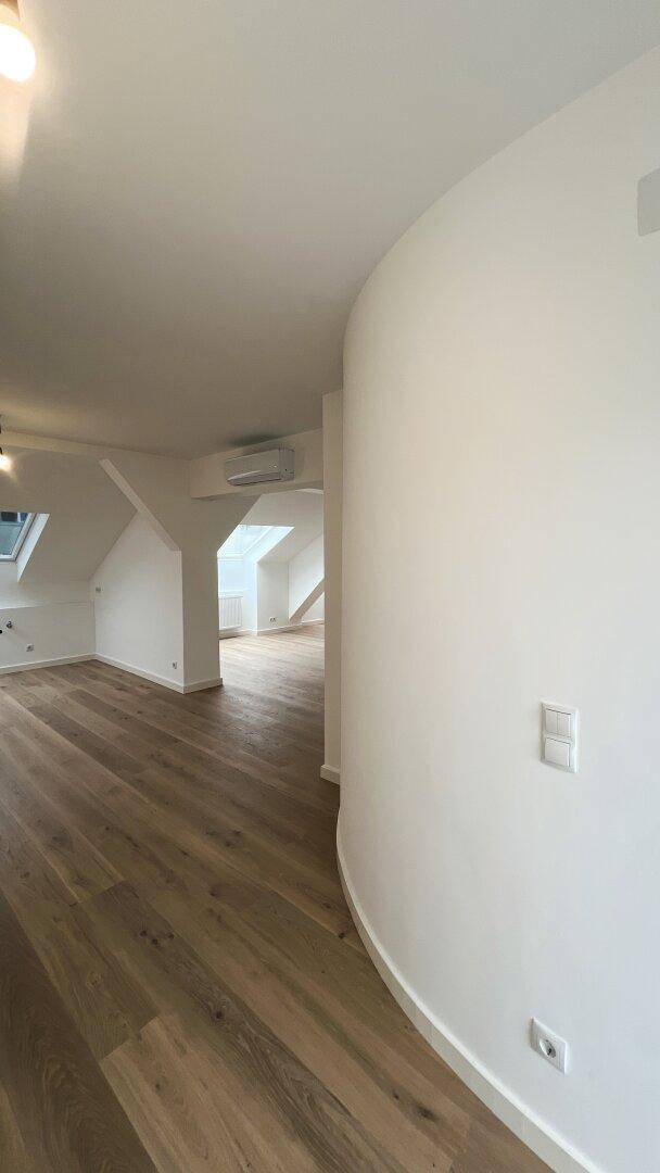 Heller Flur mit Holzboden und geschwungener Wand im modernen Dachgeschoss-Apartment.