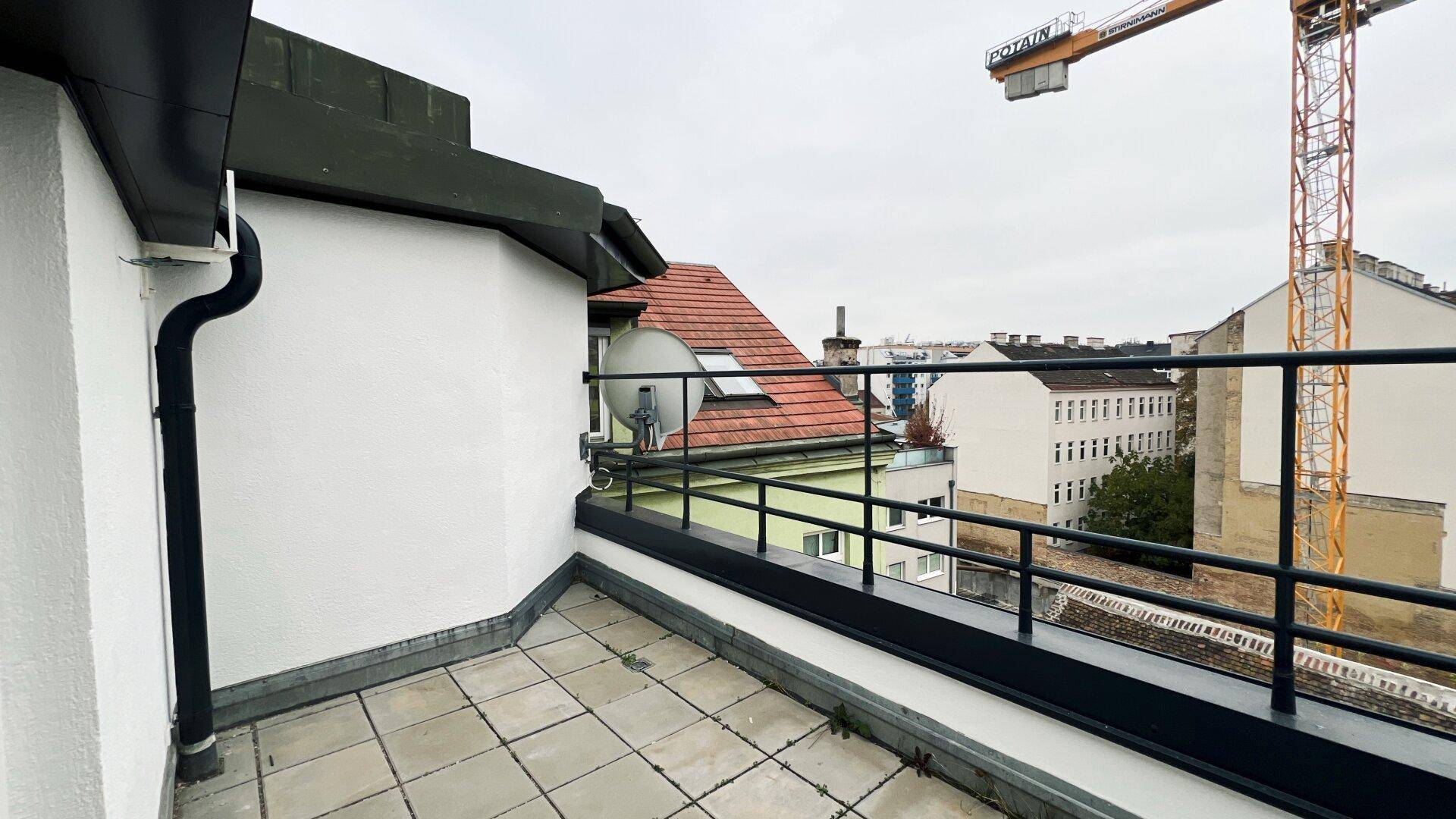 Dachterrasse mit Fliesenboden und Blick auf die Stadt und einen Baukran.