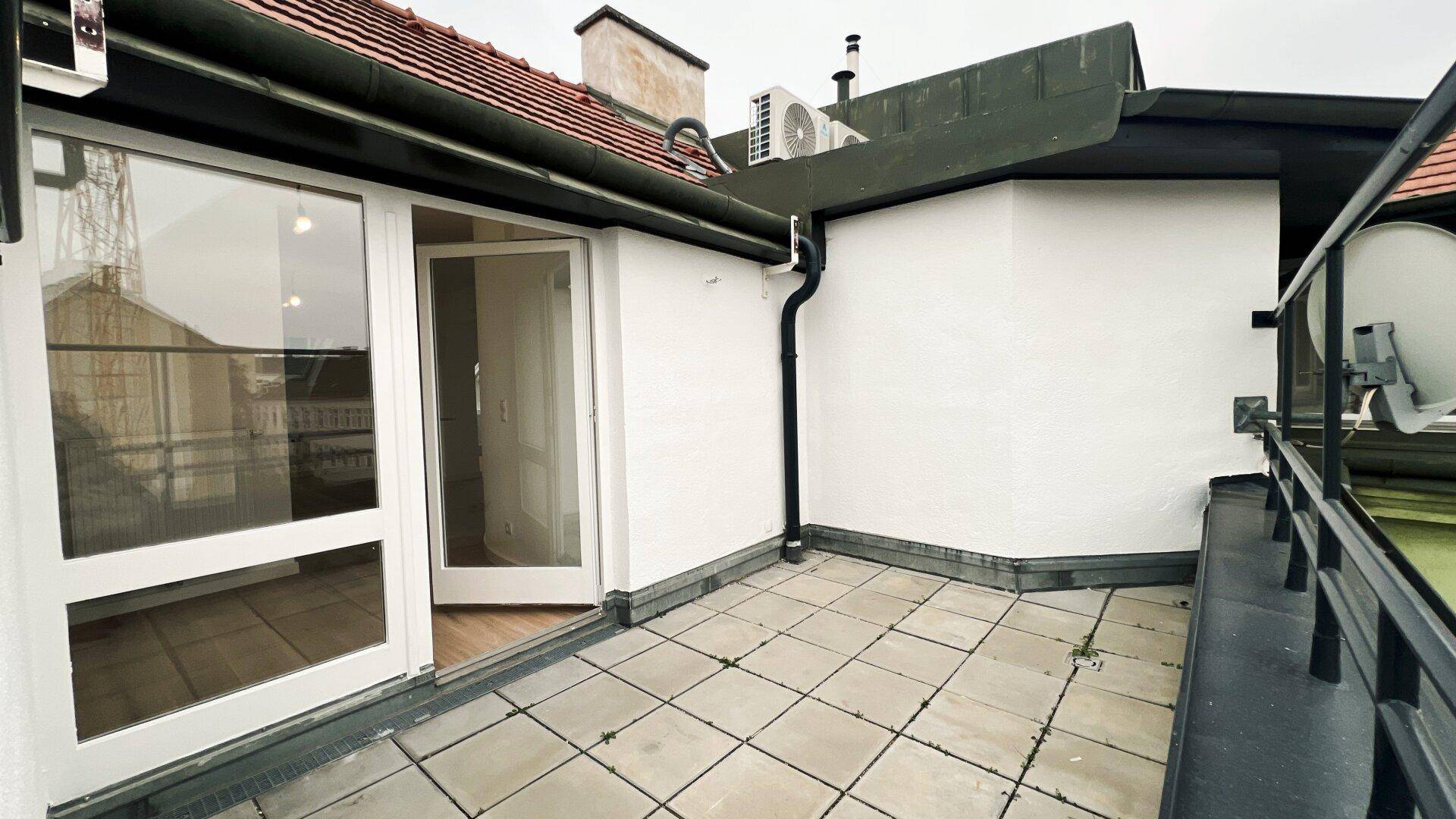 Geräumige Dachterrasse mit Fliesenboden und Blick auf die umliegenden Gebäude.