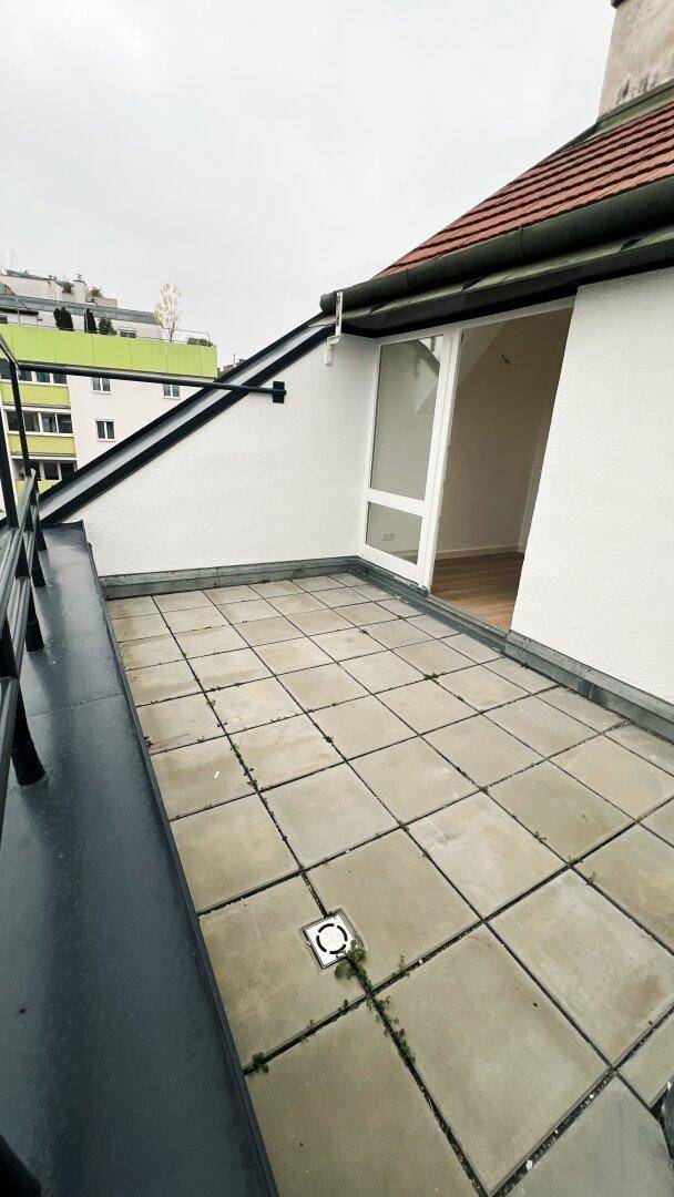Dachterrasse mit Fliesenboden und Blick auf die Stadt und die umliegenden Gebäude.
