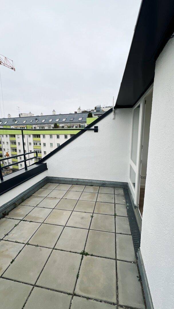 Dachterrasse mit Fliesenboden und Blick auf die Stadt und die umliegenden Gebäude.