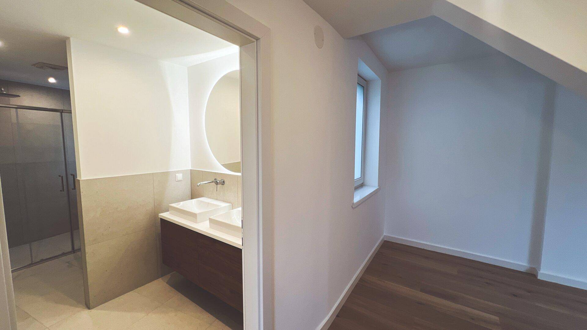 Helles Schlafzimmer mit Holzboden und Zugang zu einem modernen Badezimmer.
