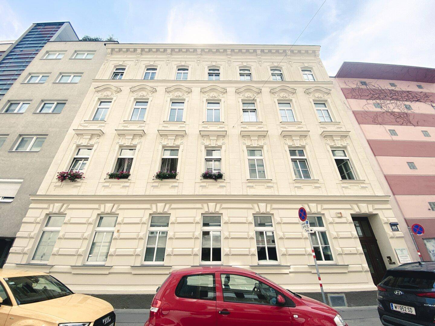 Klassische Fassade eines Altbaus mit vielen Fenstern und dekorativen Elementen.