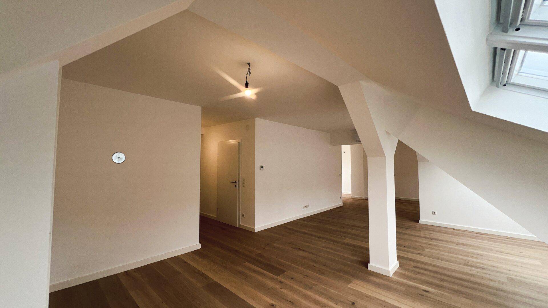 Heller Flur mit Holzboden und Blick in weitere offene Wohnbereiche im Dachgeschoss.