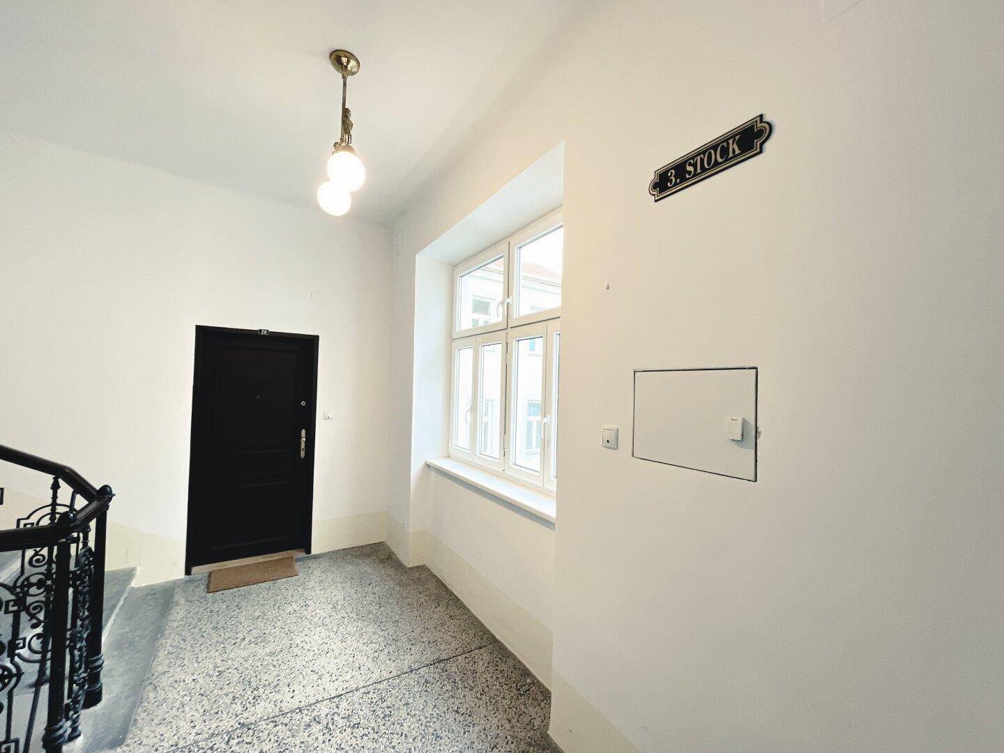 Treppenhaus mit Terrazzoboden, schmiedeeisernem Geländer und Fenster im dritten Stock.