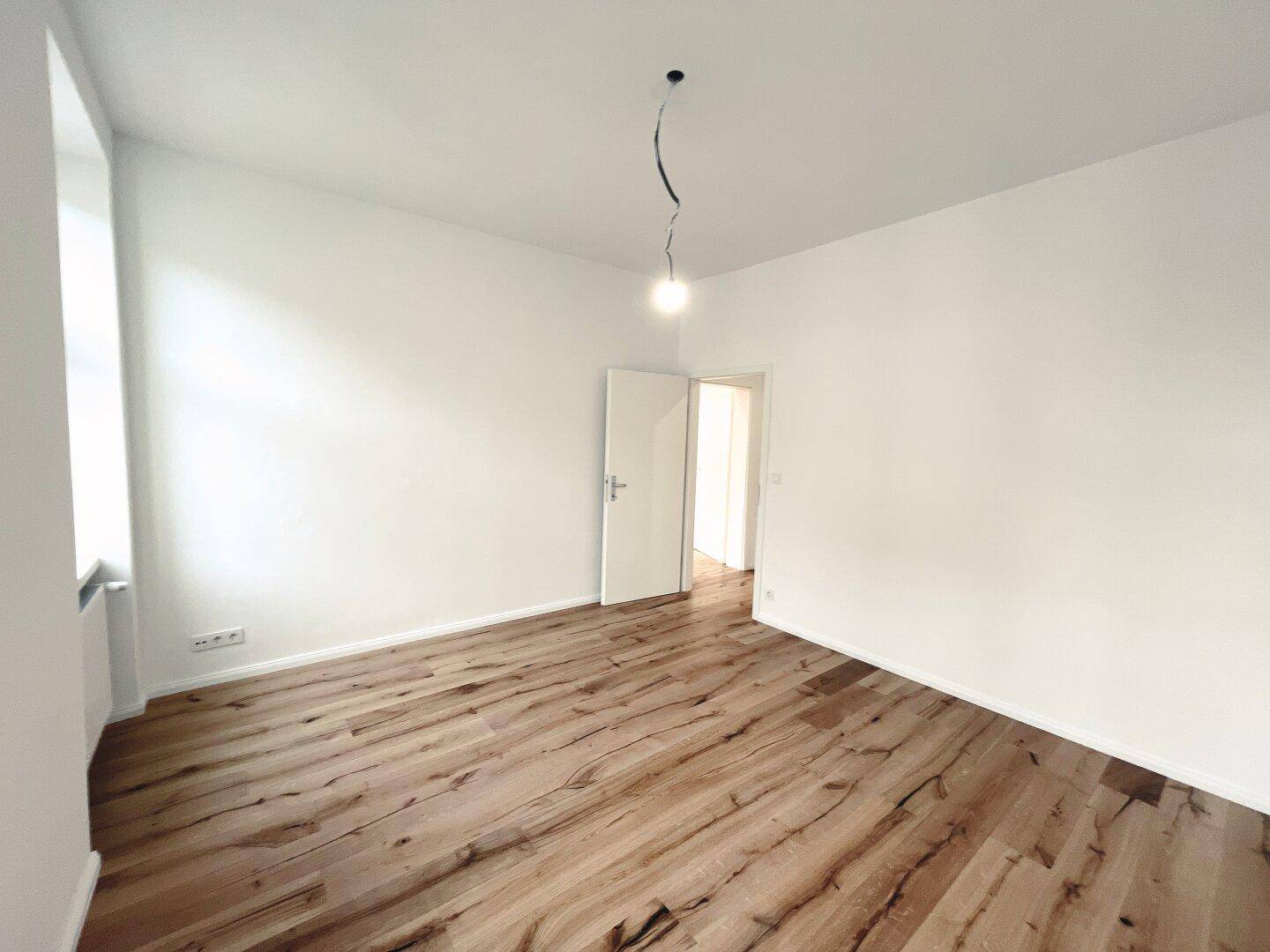 Helles Zimmer mit neuem Parkettboden und weiß gestrichenen Wänden, bereit zur individuellen Gestaltung.