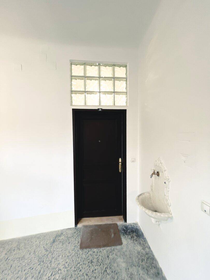 Eingangstür zu einer Wohnung mit Glasbaustein-Oberlicht und einem kleinen Wandbrunnen.
