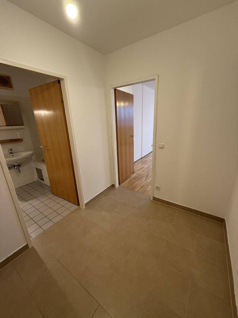 Eingangsbereich mit Fliesenboden und Türen zu verschiedenen Zimmern, inklusive Badezimmer.