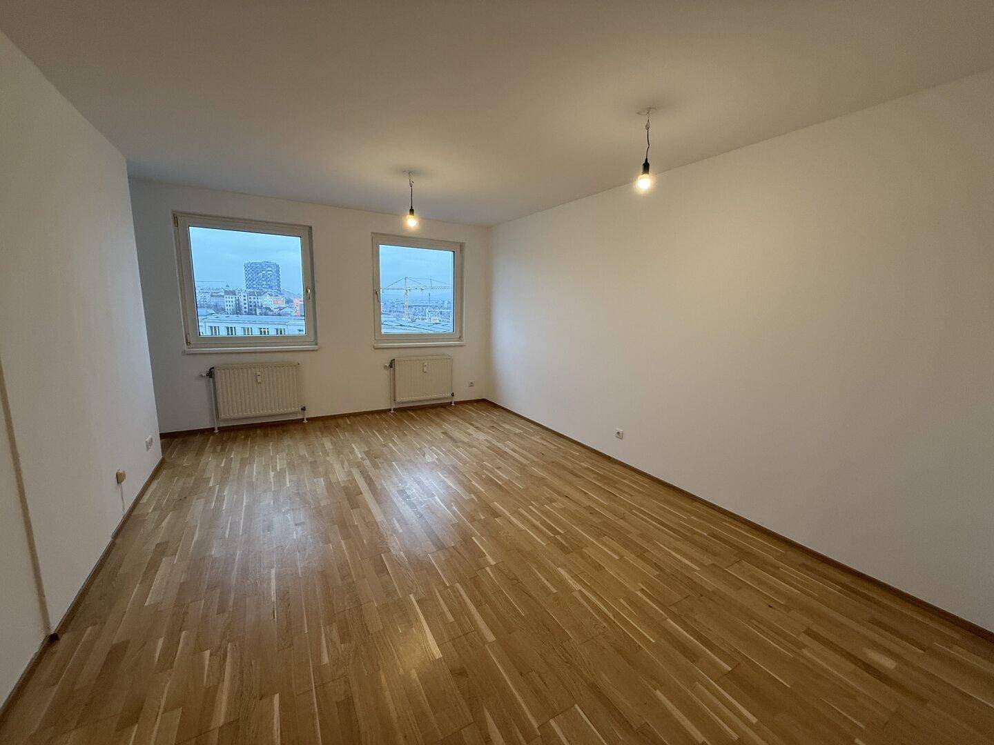 Geräumiges, helles Zimmer mit Parkettboden und zwei Fenstern, die einen Stadtblick ermöglichen.