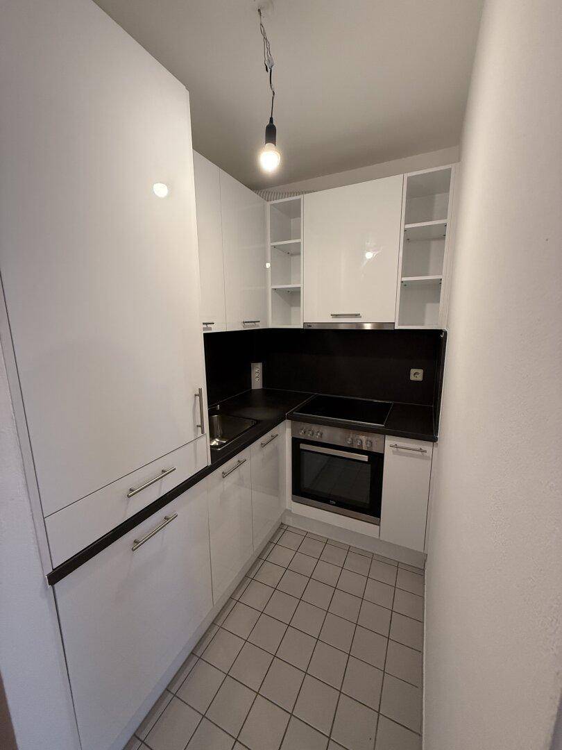 Moderne Küche mit weißen Hochglanzfronten, schwarzer Arbeitsplatte und integrierten Geräten.