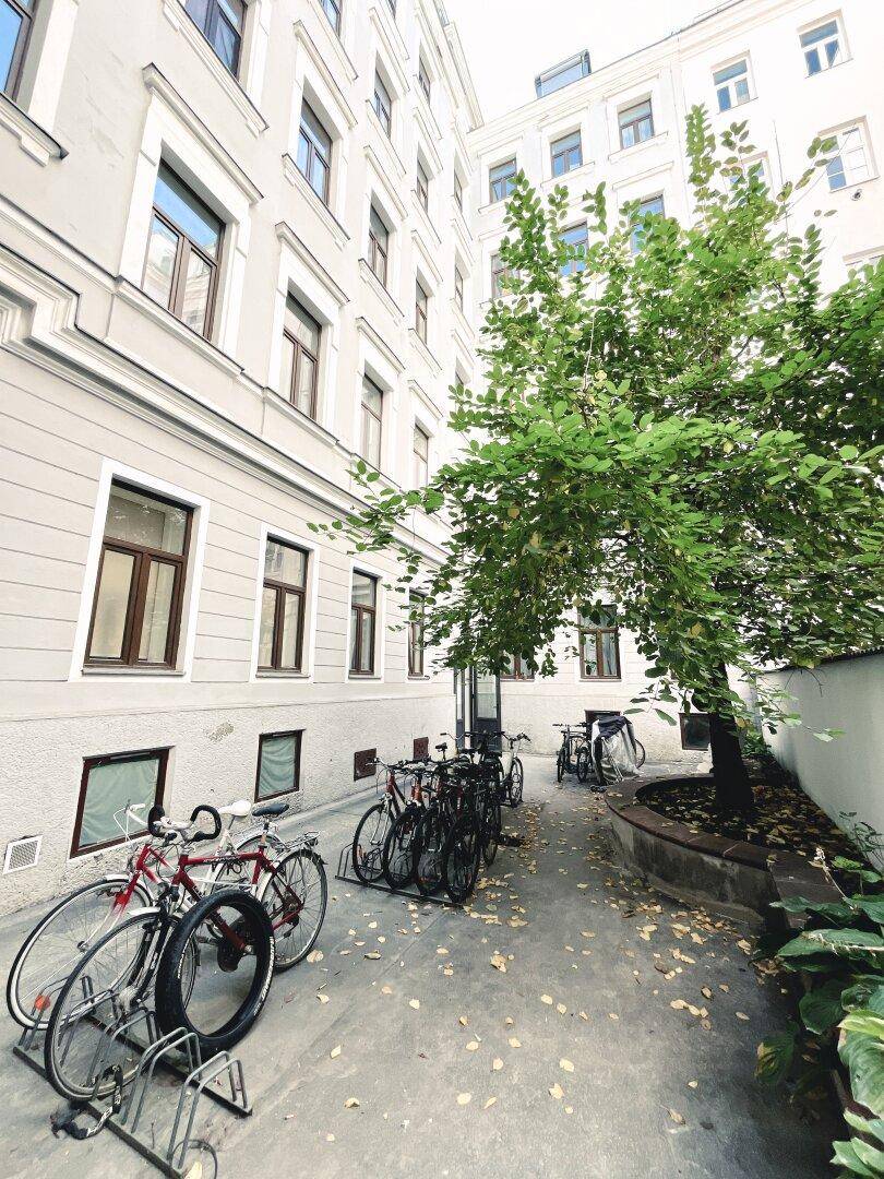 Innenhof mit Fahrradständern und einem Baum, bietet einen ruhigen Außenbereich.