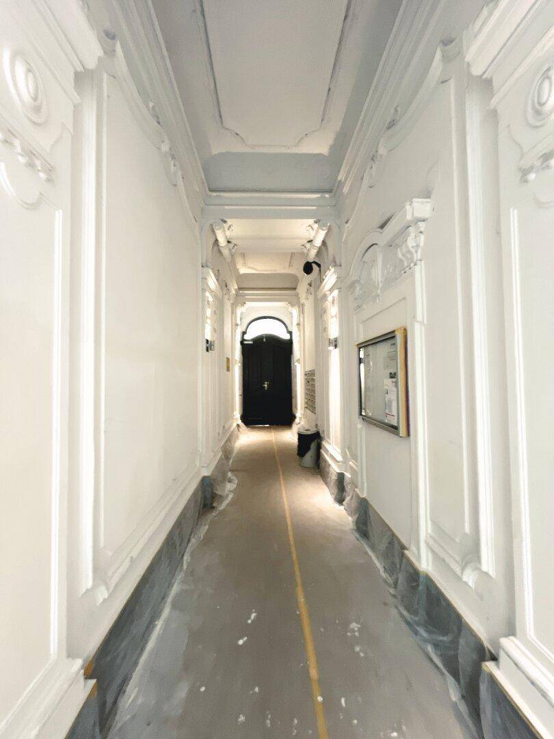 Eleganter Eingangsbereich mit Stuckverzierungen und hoher Decke, führt zum Hauptzugang.