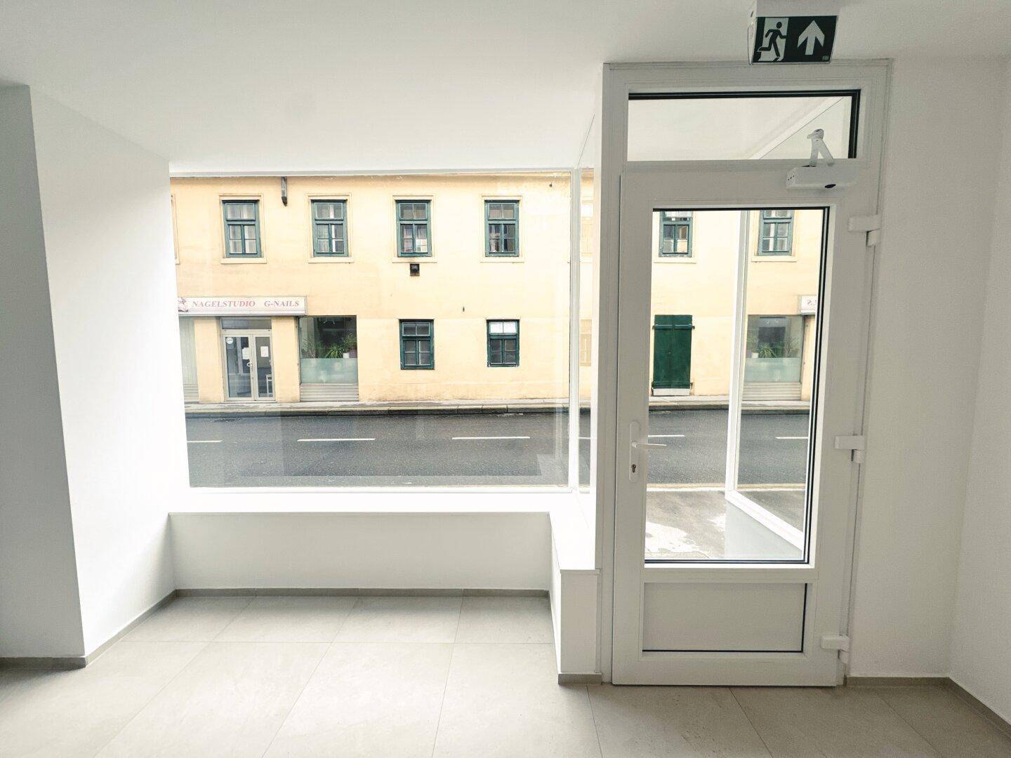 Große Schaufensterfront eines Geschäftsraums mit Blick auf die gegenüberliegende Straße und Gebäude.