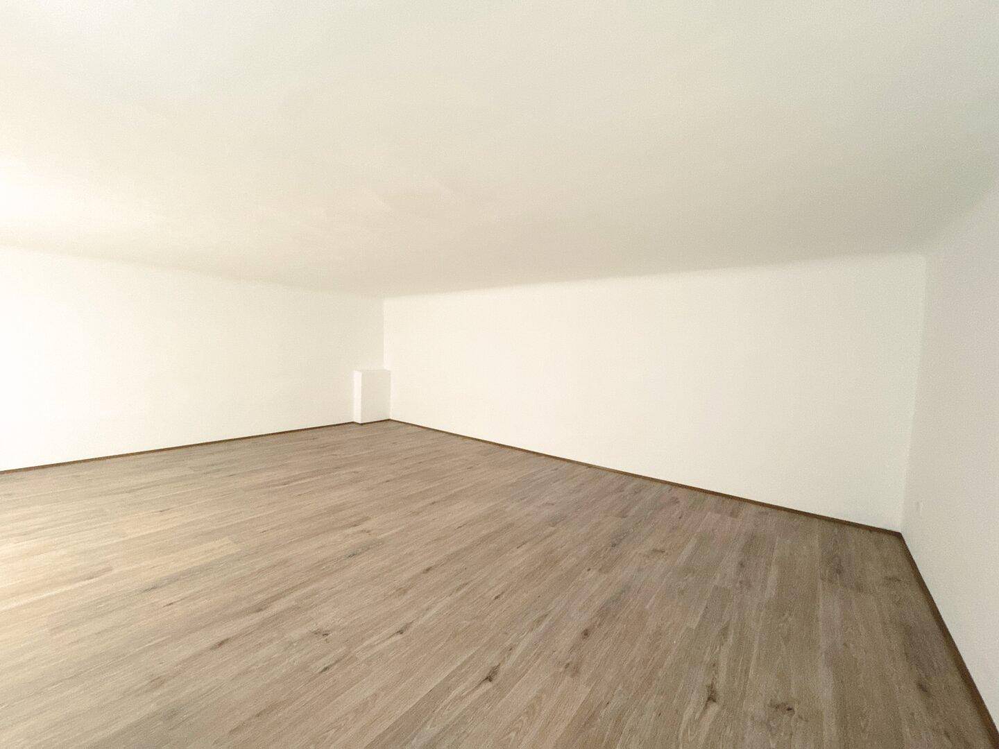 Obergeschoss eines Geschäftsraums mit hellem Laminatboden und weißen Wänden, bereit zur Gestaltung.