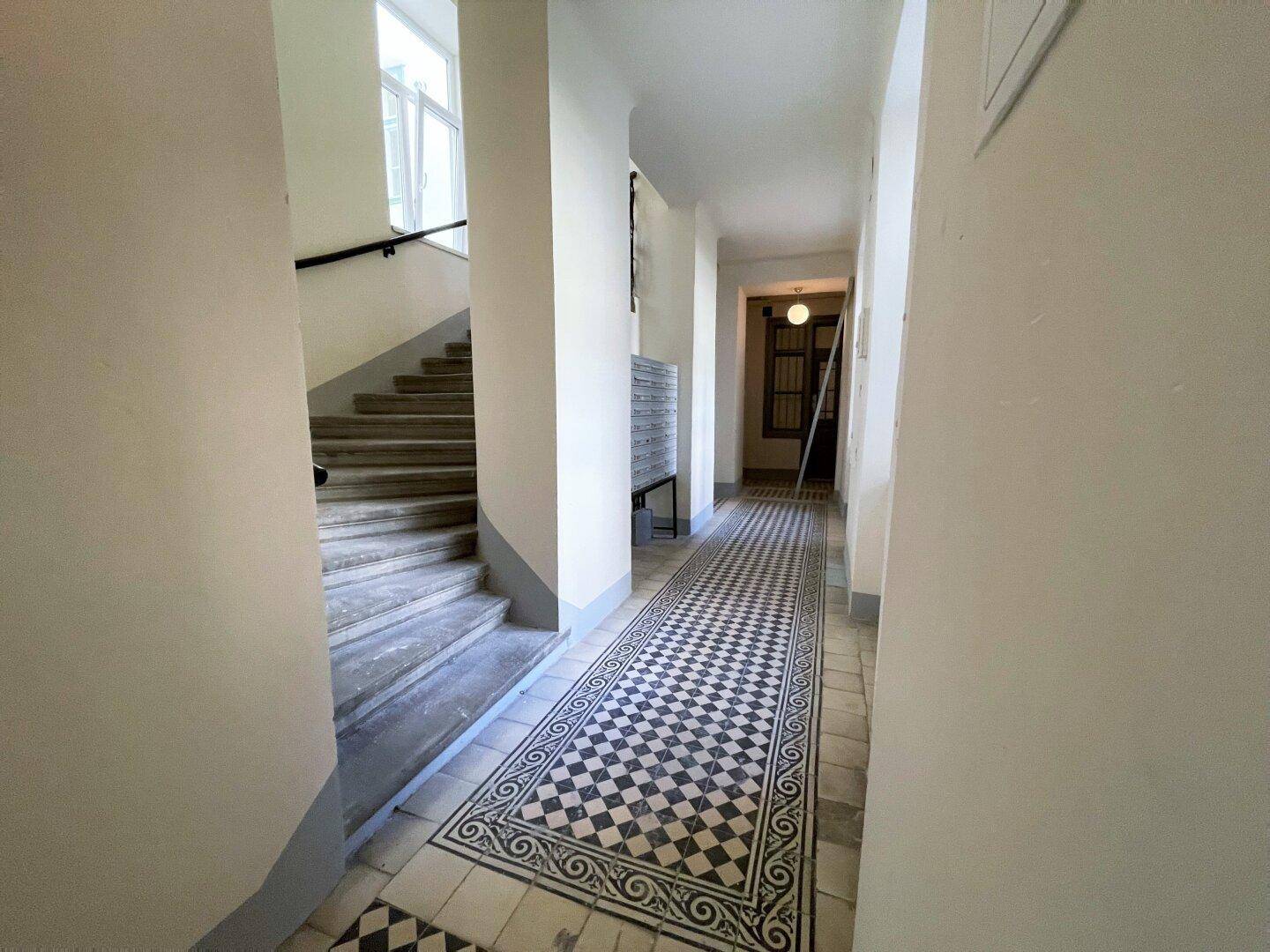 Geräumiger Flur mit Steintreppe und gemustertem Fliesenboden, führt zu einem weiteren Bereich.