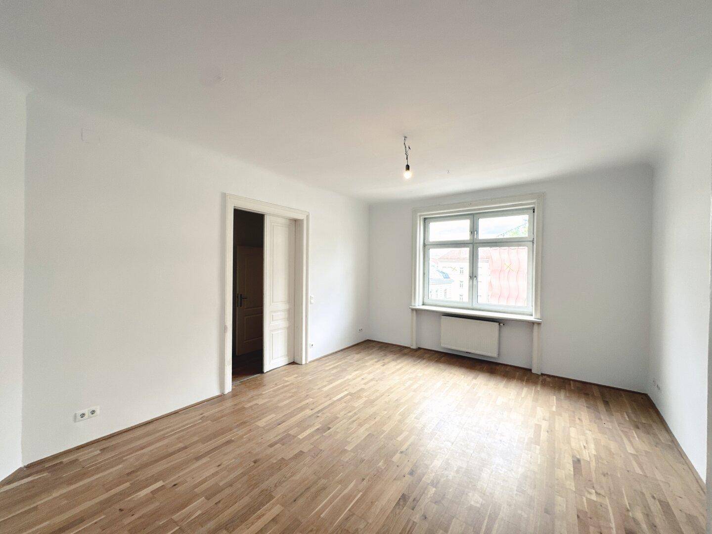 Geräumiges, helles Zimmer mit Parkettboden und Blick nach draußen, ideal für Wohnzwecke.