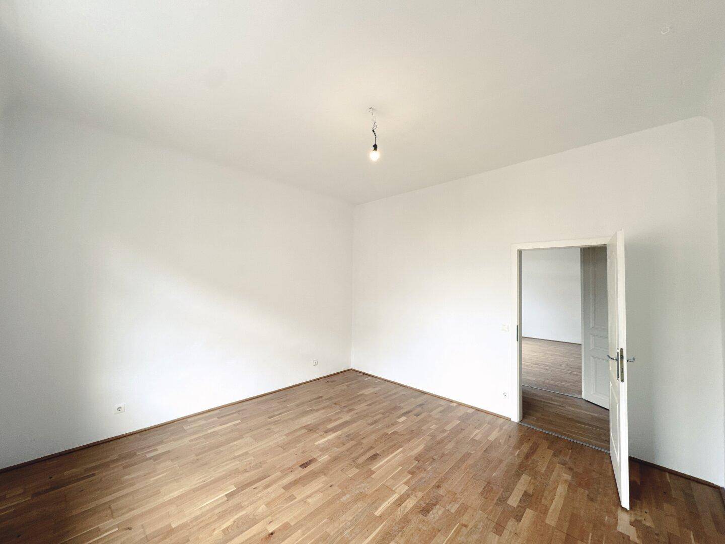 Leeres, helles Zimmer mit Parkettboden und weiß gestrichenen Wänden, bereit zum Einzug.