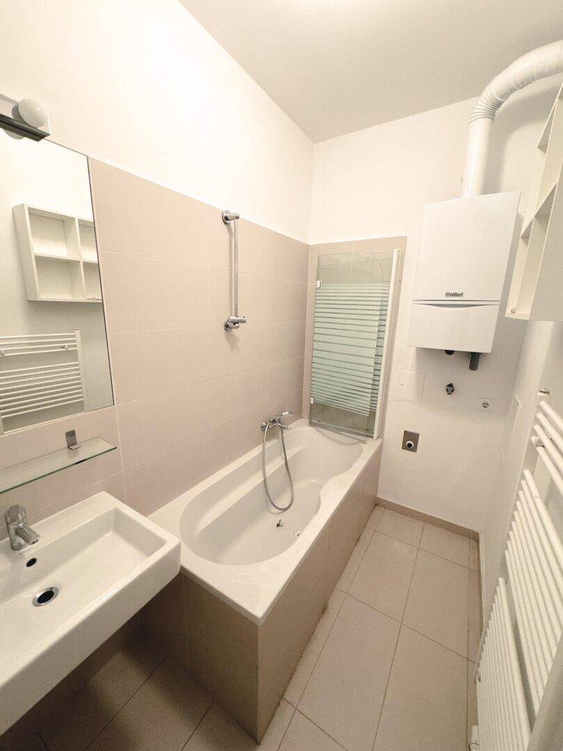 Helles Badezimmer mit Badewanne, Waschbecken und Heizkörper, funktional und sauber.