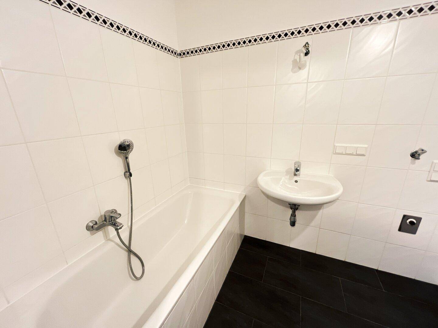 Modernes Badezimmer mit Badewanne, Waschbecken und weißen Wandfliesen.