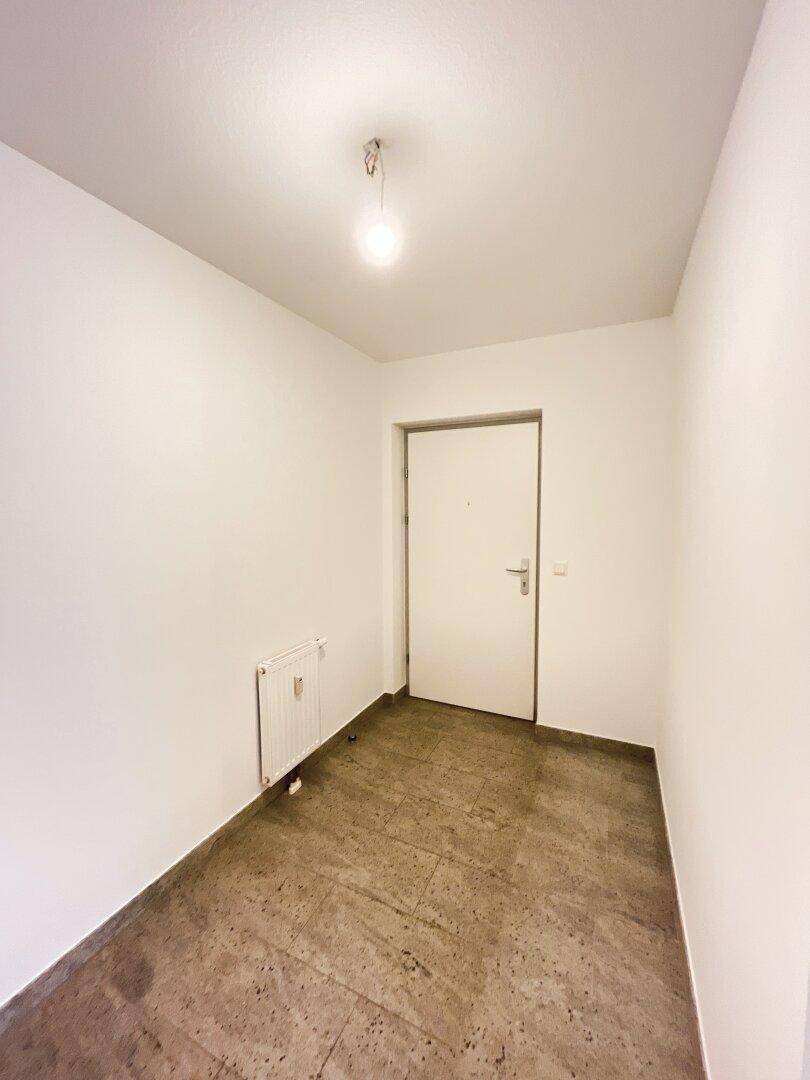 Eingangsbereich mit Fliesenboden und weißer Eingangstür, hell und einladend.