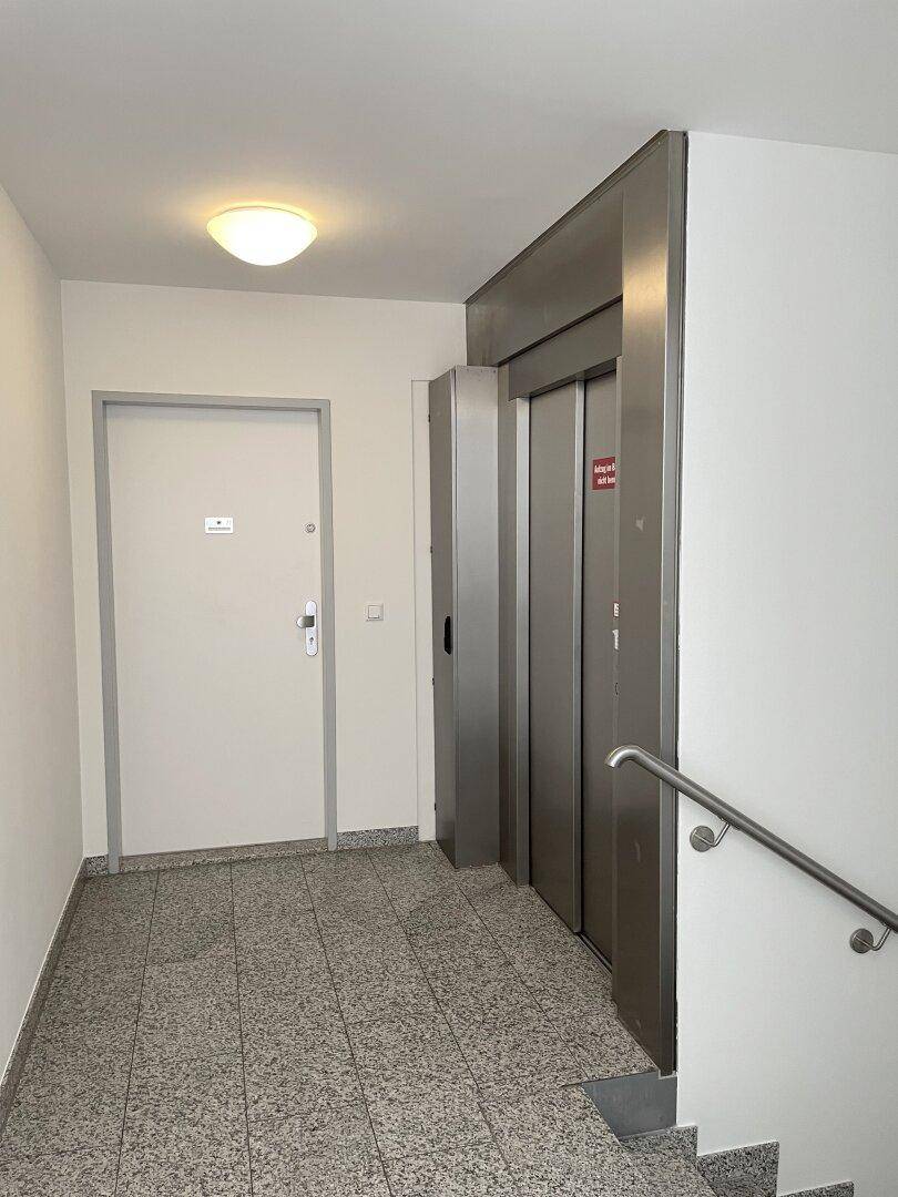 Heller Hausflur mit Aufzug und Treppenhauszugang, gut gepflegt und funktional.