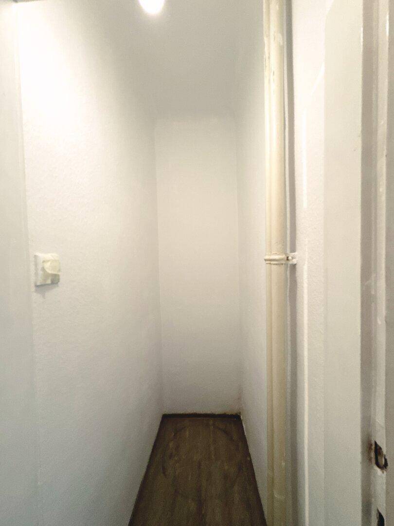Kleiner Abstellraum mit schmalem Grundriss und sichtbaren Rohrleitungen.