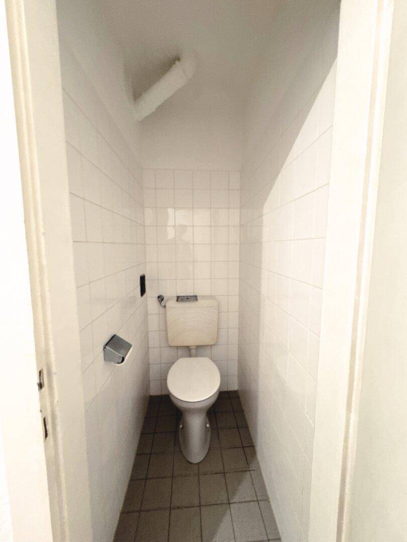 Separate Toilette mit Fliesen an Wänden und Boden, ausgestattet mit WC.