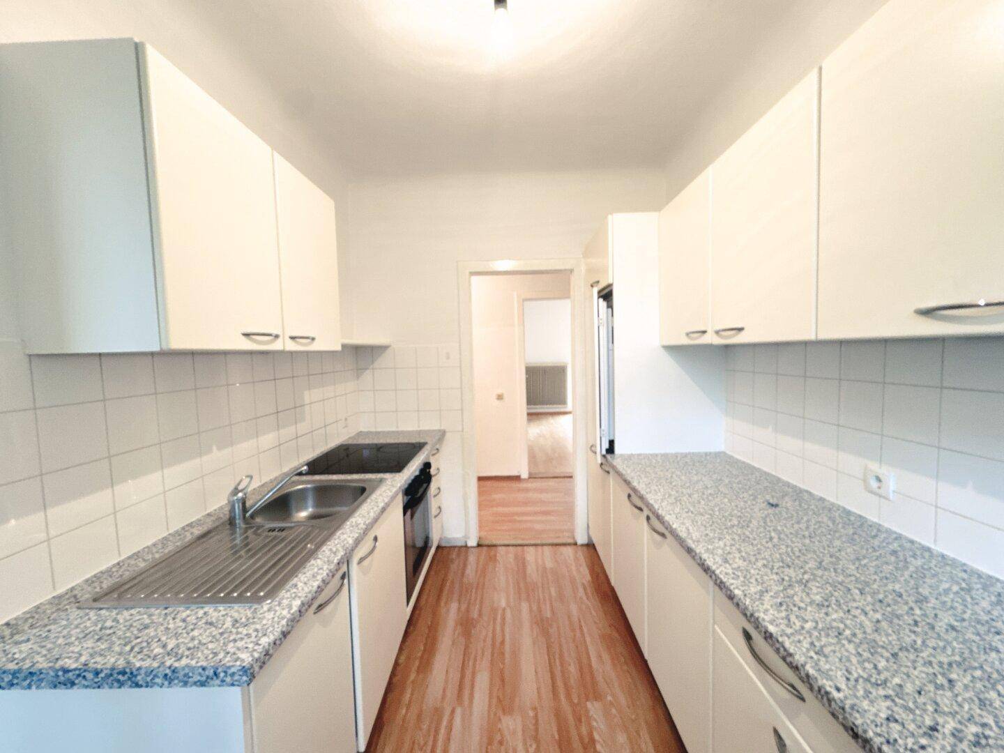 Funktionale Küche mit weißen Schränken, Granitarbeitsplatten und Fliesenrückwand.