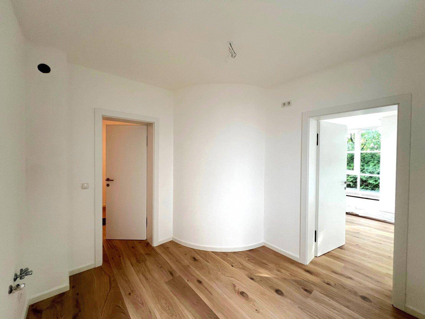 Heller Flur mit Holzboden und mehreren Türen, die zu anderen Räumen führen.