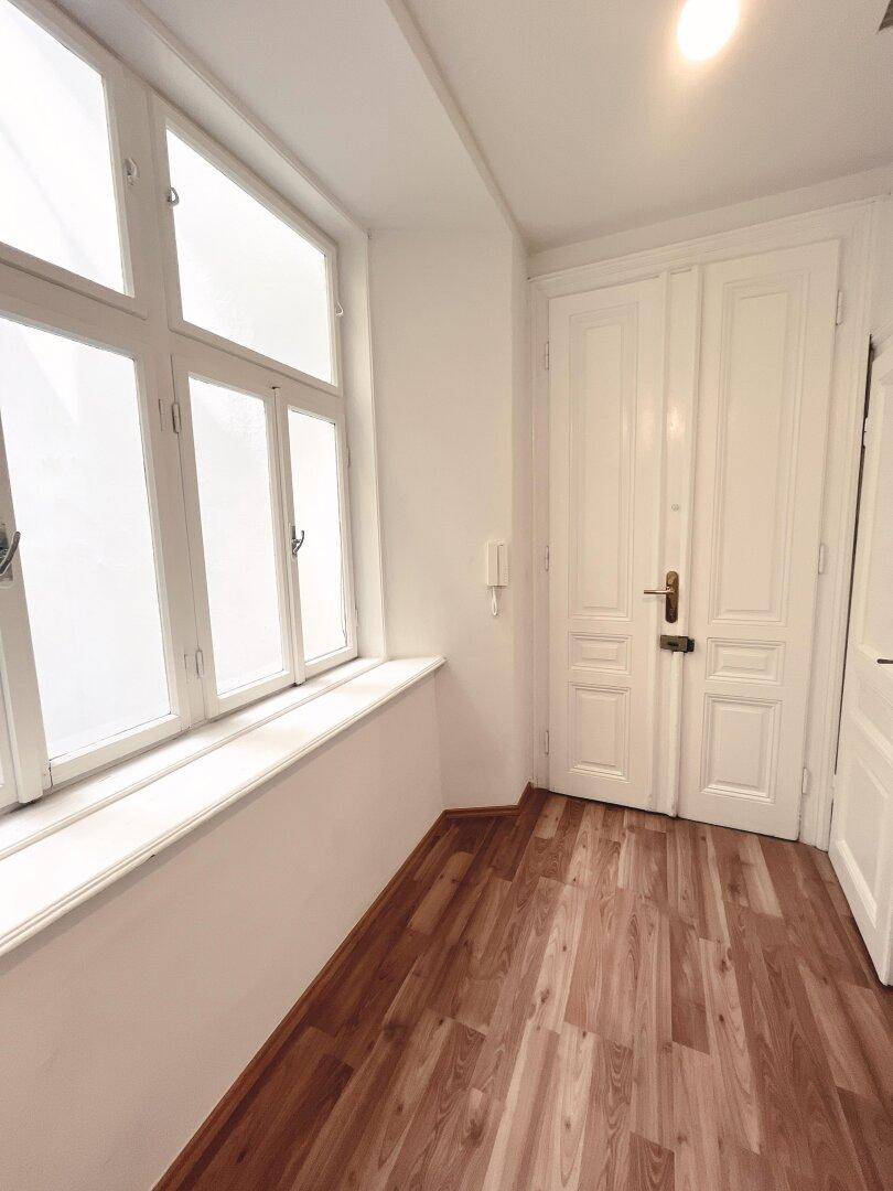 Lichtdurchfluteter Flur mit breitem Fenster und eleganten weißen Doppeltüren.