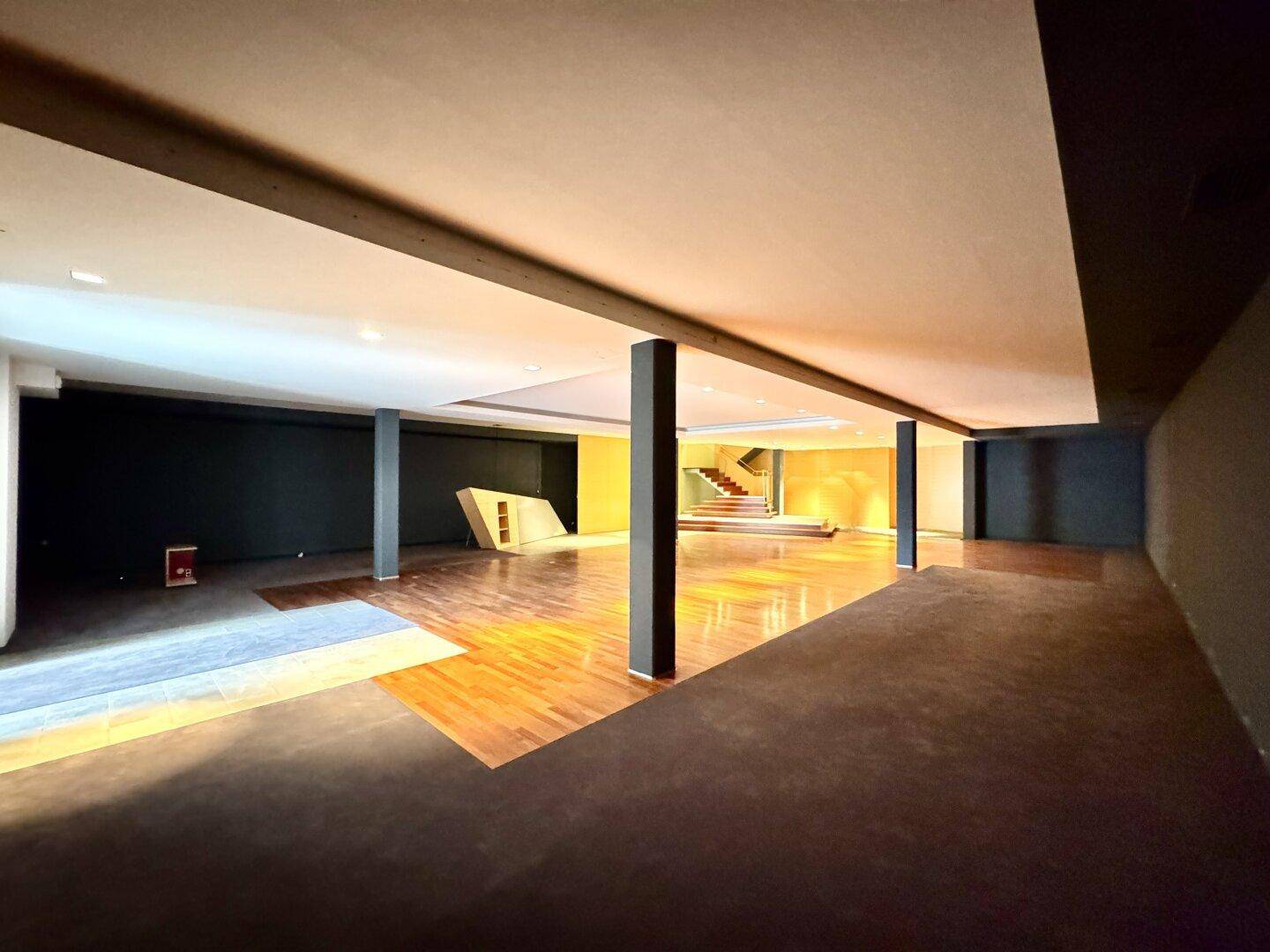 Geräumiger Gewerberaum mit glänzendem Holzboden, dunklen Wänden und einer modernen, offenen Gestaltung.
