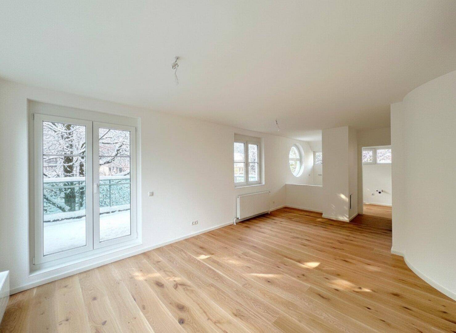 Geräumiges, helles Wohnzimmer mit Eichenparkett, großen Fenstern und Blick auf die verschneite Natur.