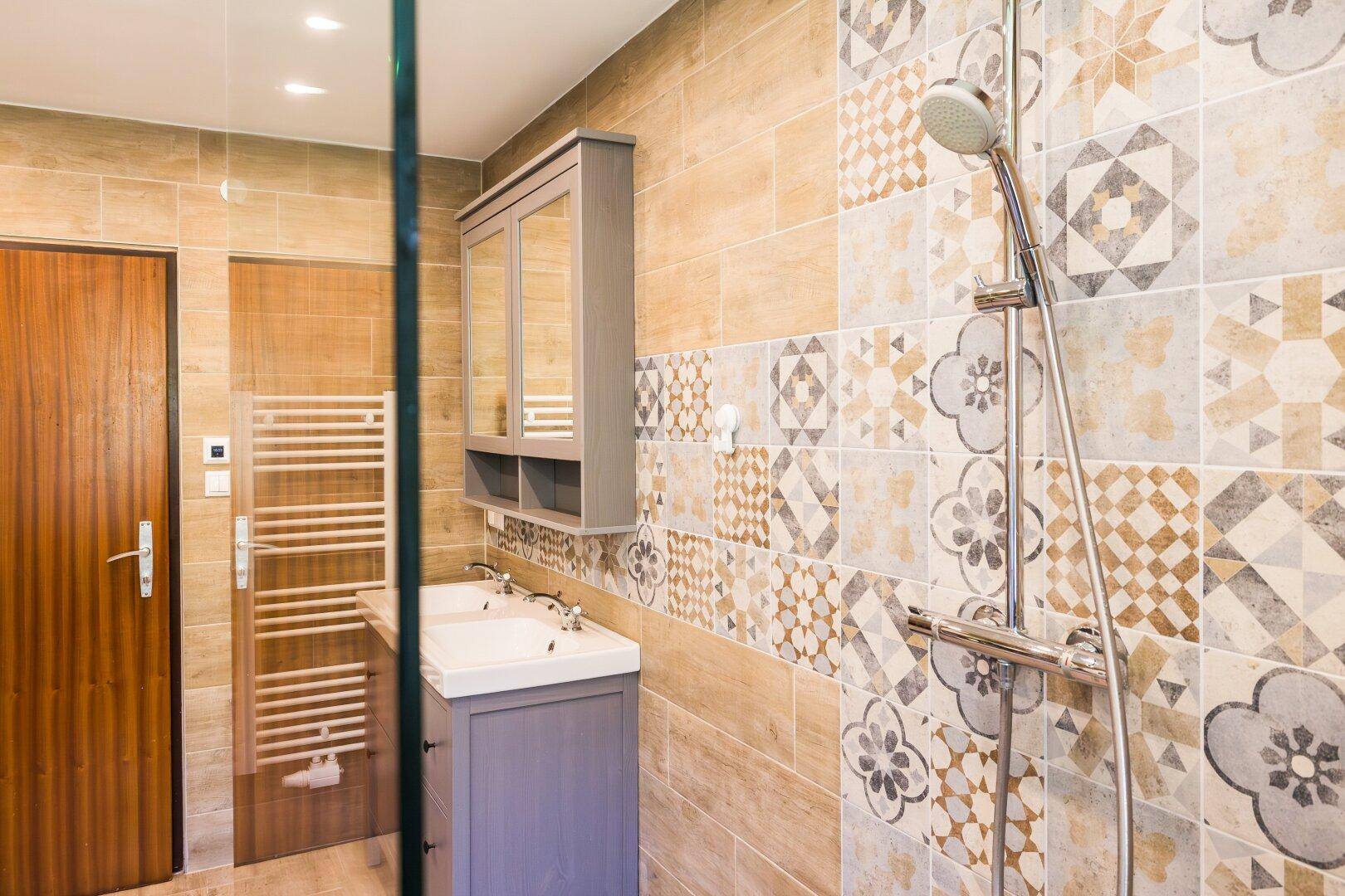 Helles Badezimmer mit moderner Dusche, Doppelwaschbecken und Handtuchheizkörper.