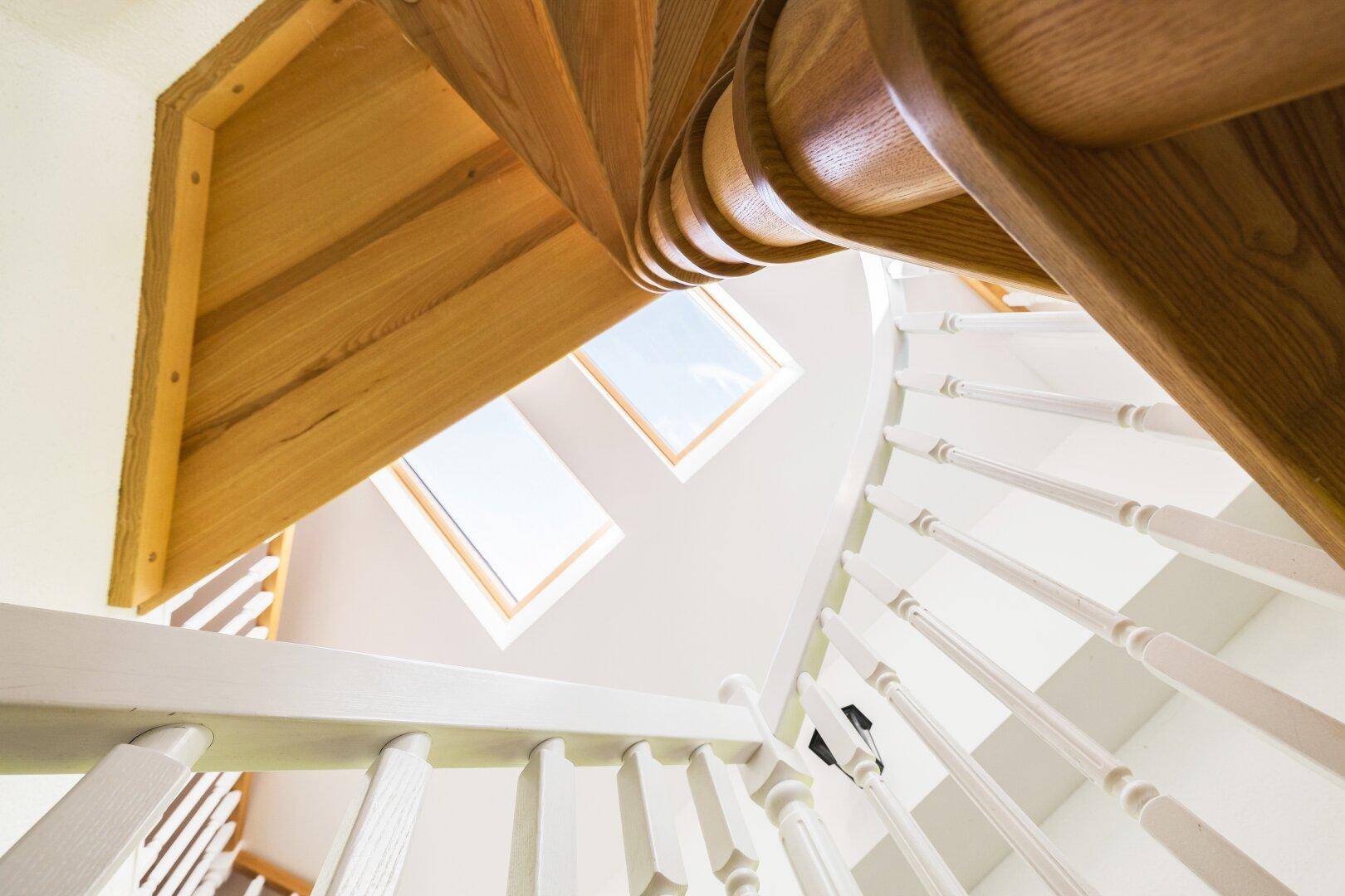 Blick nach oben auf die Wendeltreppe mit zwei Dachfenstern, die viel Licht spenden.