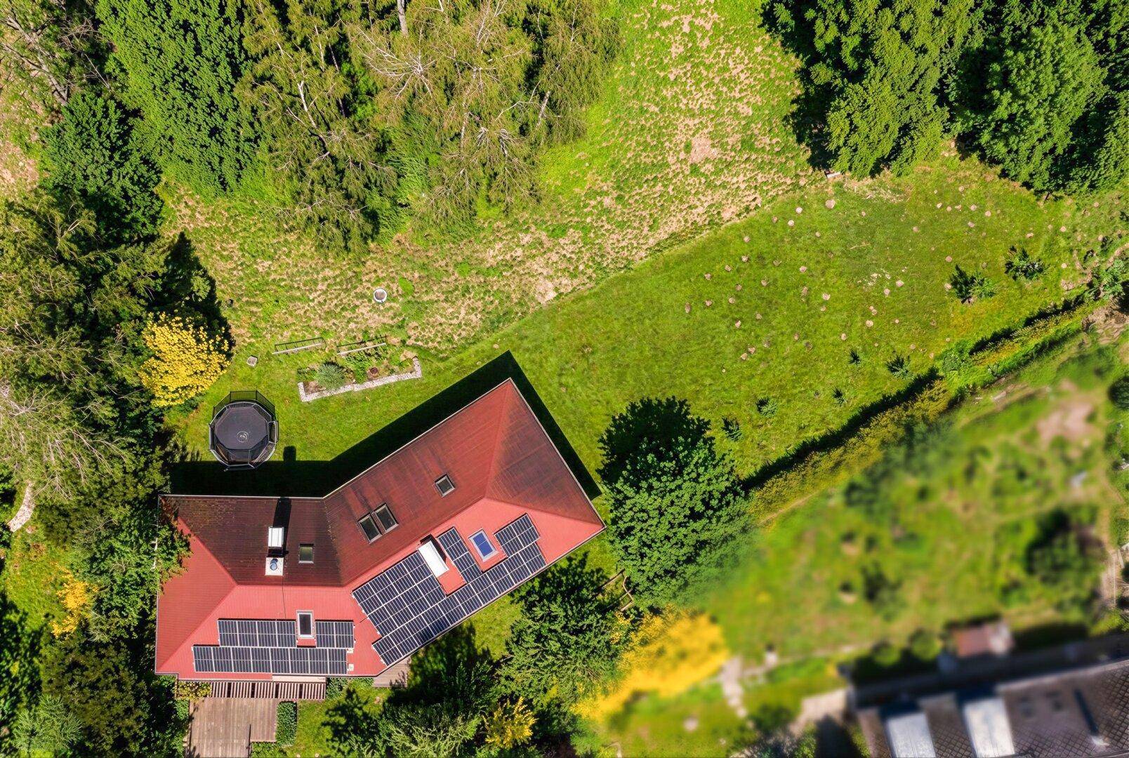 Luftaufnahme des Hauses mit Solarpaneelen auf dem Dach und großem, grünem Grundstück.