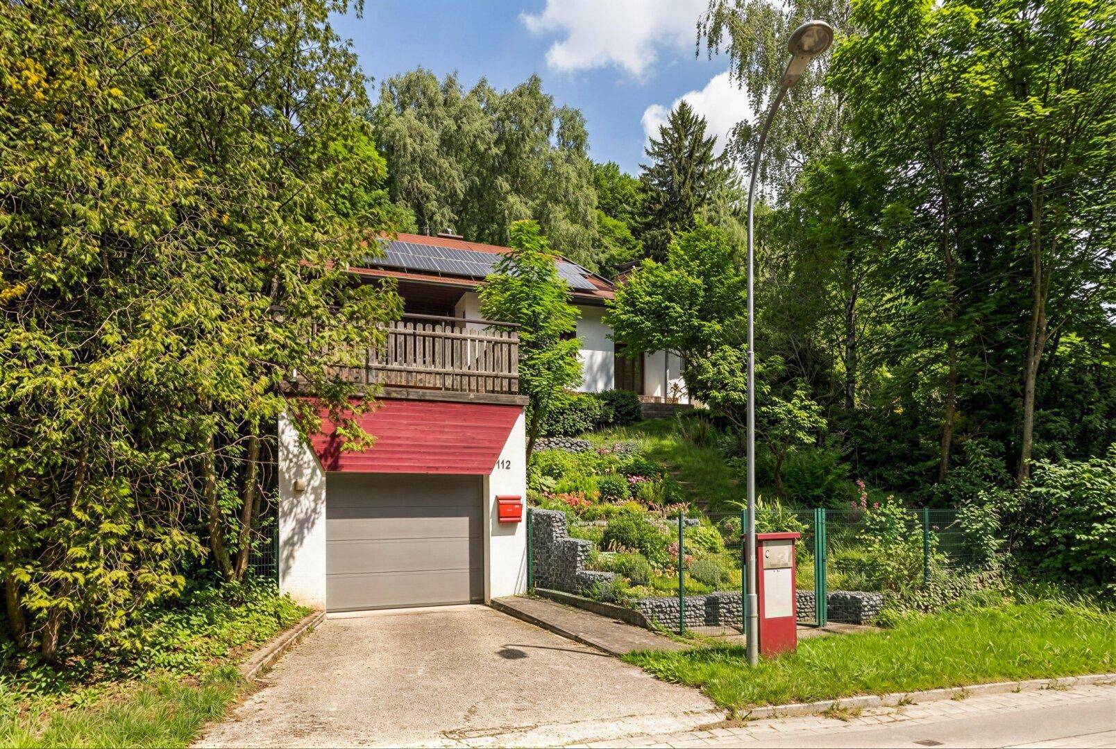 Ansicht des Hauses mit Garage, Auffahrt und Photovoltaikanlage auf dem Dach.