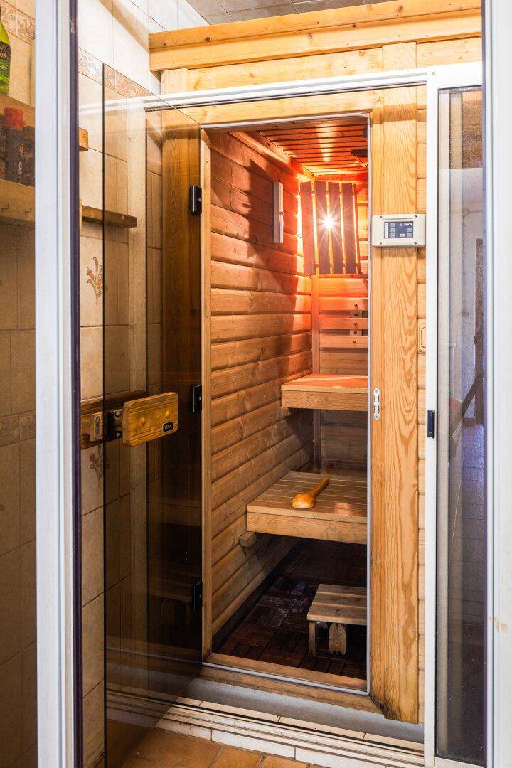 Innenansicht der Holzsauna mit Bänken und Heizofen für entspannende Momente.