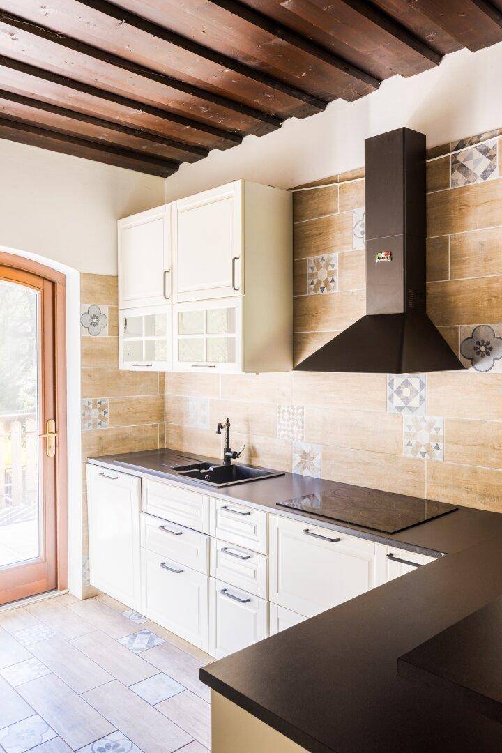 Helle Küche mit weißen Schränken, dunkler Arbeitsplatte und modernen Fliesen an der Wand.