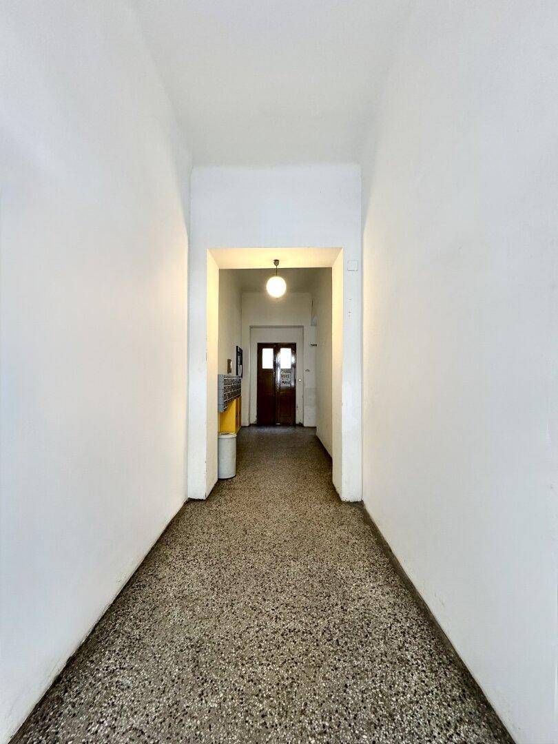Langer Eingangsbereich mit Terrazzoboden und Zugang zum Treppenhaus.