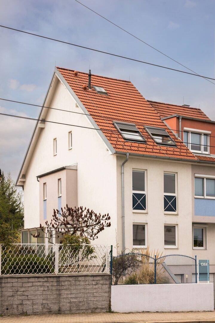 Wohngebäude mit Satteldach, Gaubenfenstern und einer gepflegten Fassade an einer ruhigen Straße.
