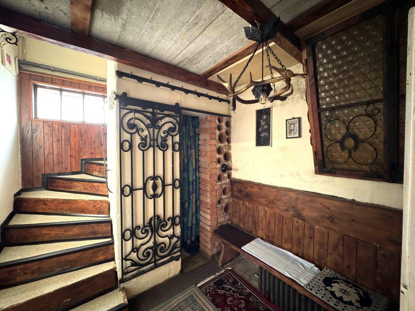 Rustikaler Kellerbereich mit Steinwänden, Holzvertäfelung und schmiedeeisernem Tor.