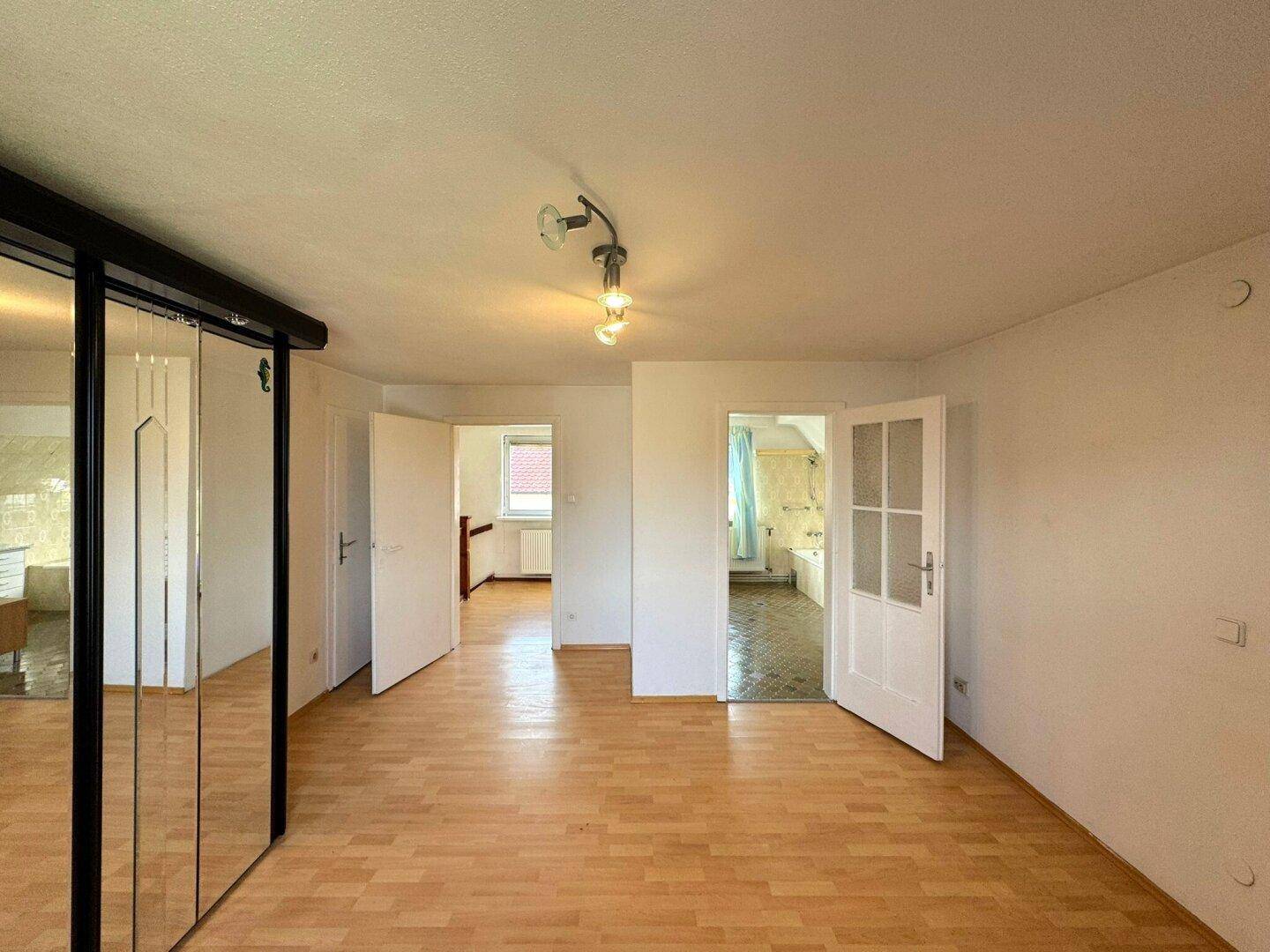 Schlafzimmer mit Laminatboden und Zugang zu einem angrenzenden Badezimmer.