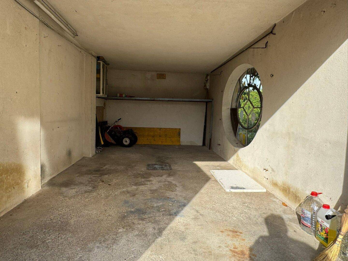 Geräumige Garage mit Betonboden und einem runden Fenster.