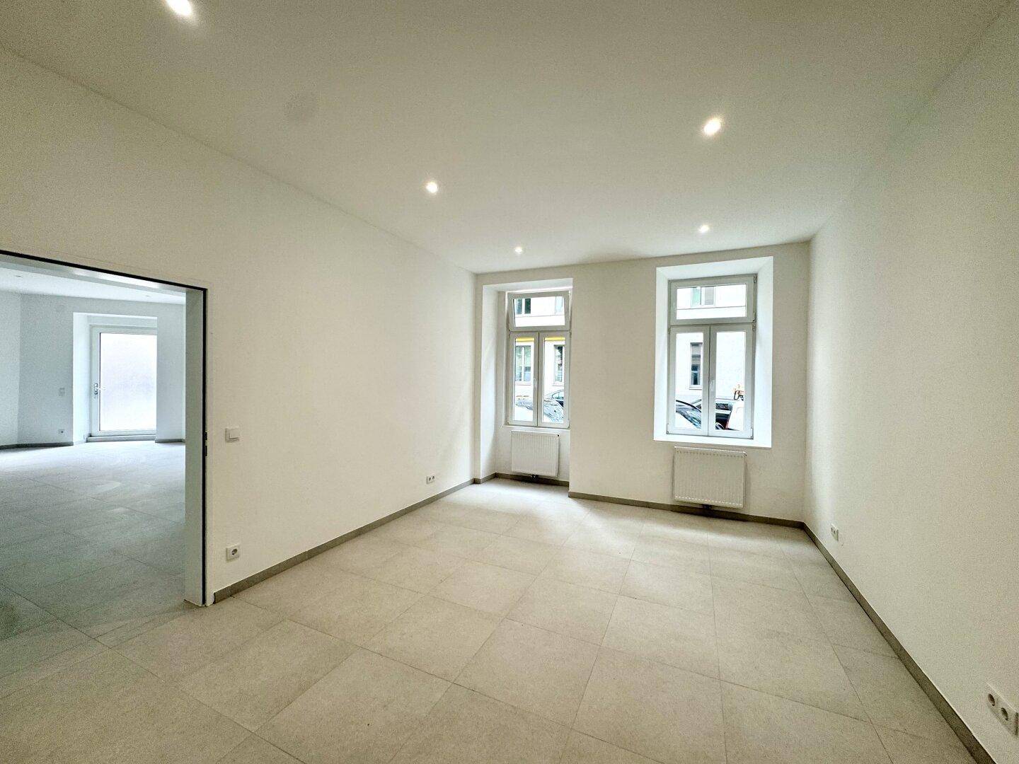 Heller, leerer Raum mit Fliesenboden und Fenstern, die viel Tageslicht hereinlassen, bereit zur Gestaltung.