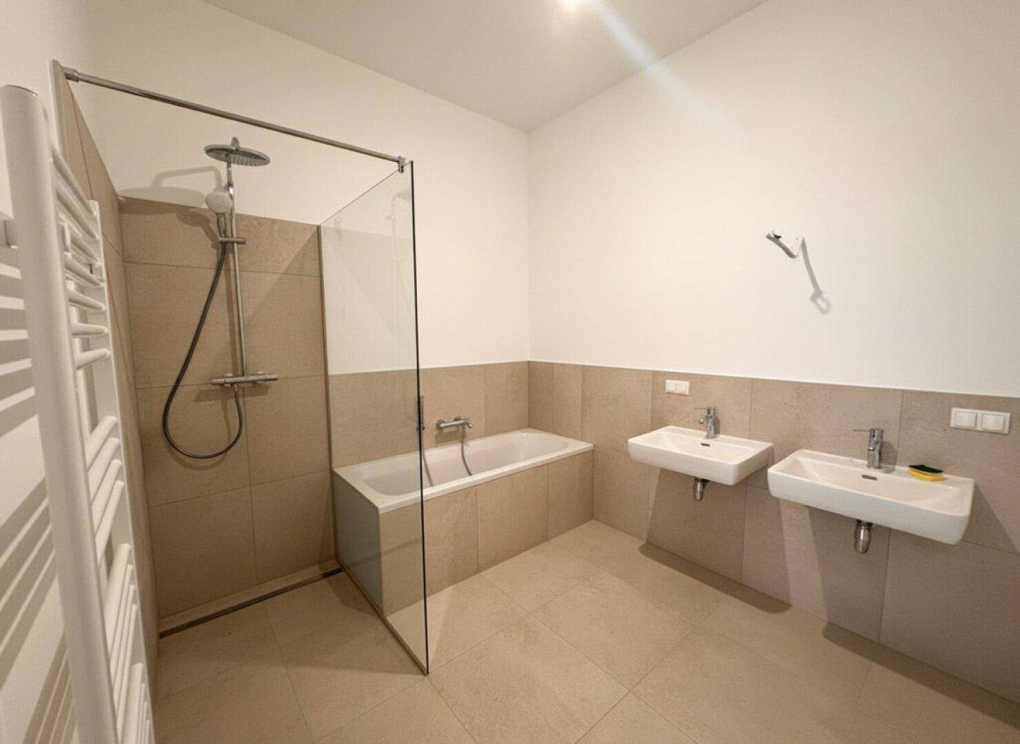 Modernes Badezimmer mit Badewanne, Dusche, Doppelwaschbecken und Handtuchheizkörper.