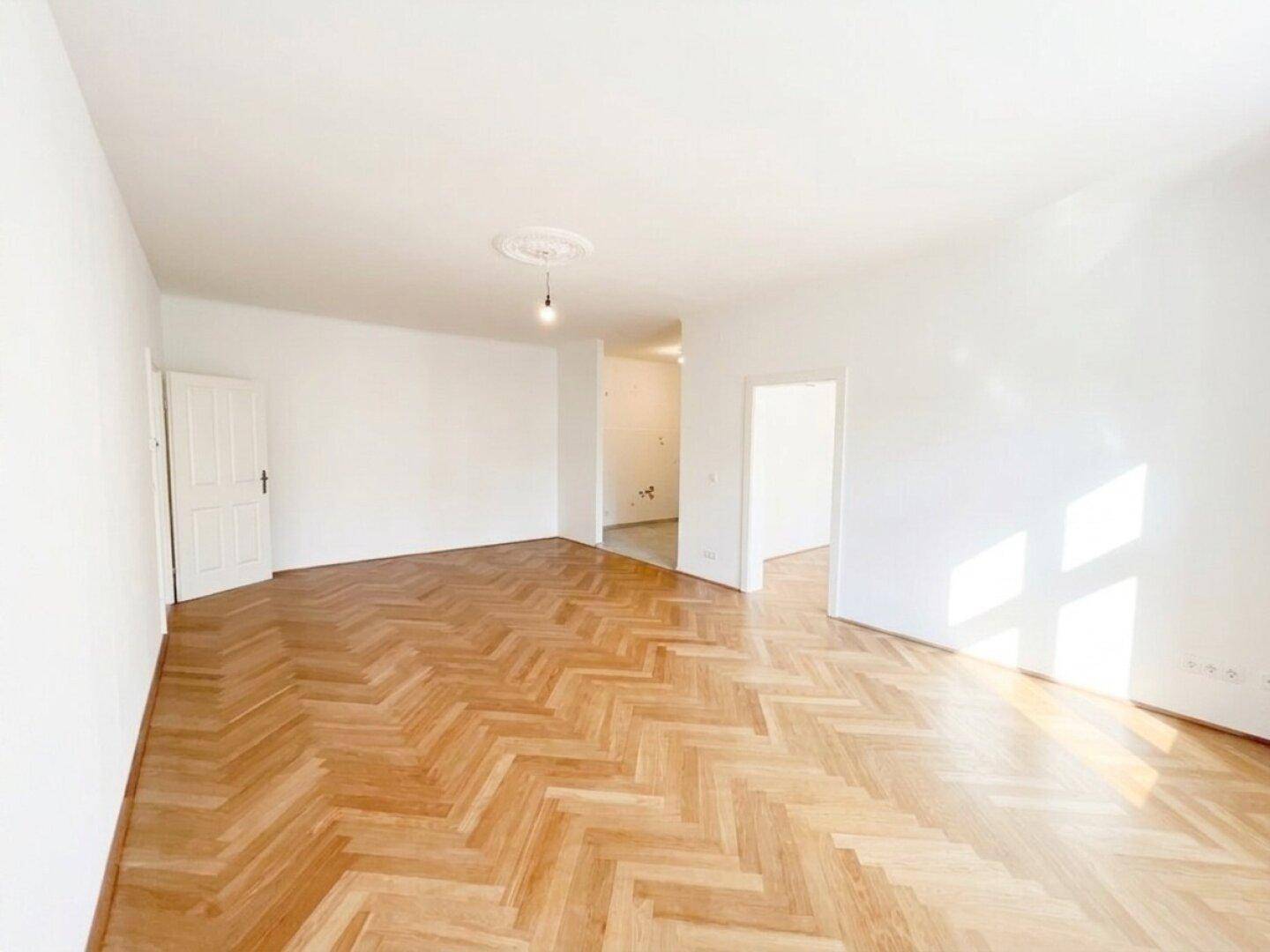 Heller Wohnraum mit Fischgrätparkett und viel Tageslicht, ideal für eine offene und freundliche Atmosphäre.